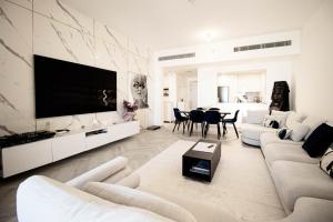 a living room with white furniture and a large flat screen tv at Burj Al Arab Front 2 Bedroom in Dubai