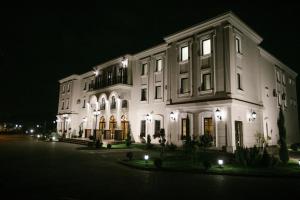 Hotel Beli Dvor في تشاتشاك: مبنى أبيض كبير في الليل مع أضواء