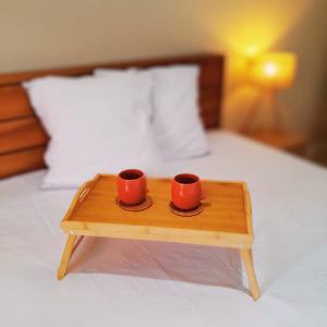 duas chávenas vermelhas numa bandeja de madeira numa cama em Studio Karaïbes em Sainte-Anne