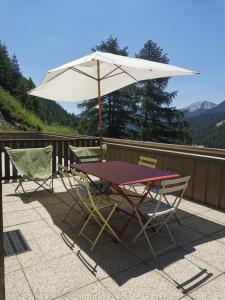- une table et des chaises sous un parasol sur la terrasse dans l'établissement Appartement lumineux et calme - La Foux-Mercantour, à Allos