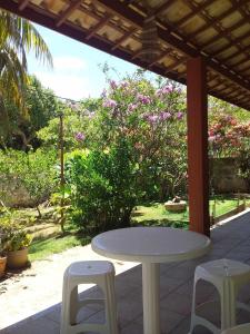 einen weißen Tisch und zwei Hocker auf einer Terrasse in der Unterkunft Casa de Praia Itacimirim Bahia in Camassari