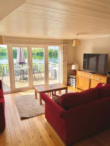 a living room with a red couch and a television at The Cotswolds Lakeside - Kinsale Lodge,Spring Lake in South Cerney