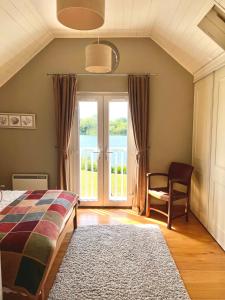 a bedroom with a bed and a chair and a window at The Cotswolds Lakeside - Kinsale Lodge,Spring Lake in South Cerney