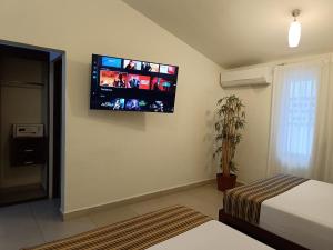 a bedroom with a flat screen tv on the wall at Grand City Hotel Cancun in Cancún