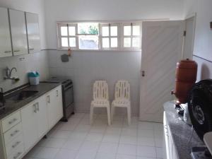 eine Küche mit weißen Schränken und 2 weißen Stühlen in der Unterkunft Casa de Praia Itacimirim Bahia in Camassari + 12 Fotos