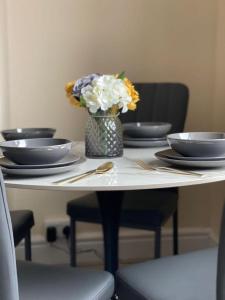 a table with plates and a vase of flowers on it at St James House - Sleeps 8! in Leeds