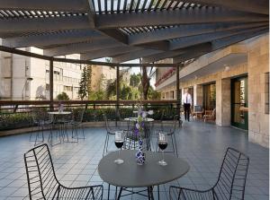 a patio with two tables and chairs with wine glasses at Prima Kings Hotel in Jerusalem