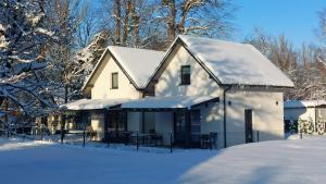 a white house covered in snow with tables and chairs at Spokojny zakątek in Ustroń