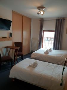 een hotelkamer met 2 bedden, een tafel en een raam bij Auberge Communale de la Fruitière in Péron