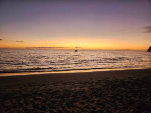 a sunset on the beach with a boat in the water at CASA TONINO in Mogán