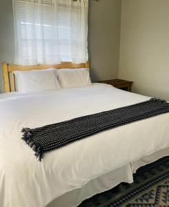 a bedroom with a large white bed with a window at Pule's Home in Maseru