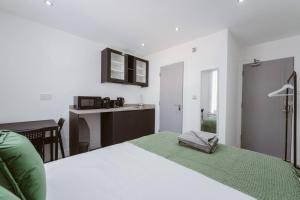 a bedroom with a bed with a green blanket and a desk at Fulham Guest Studios 268 in London