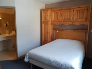 a bedroom with a white bed and wooden cabinets at Auberge Communale de la Fruitière in Péron