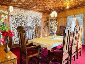 a dining room with a wooden table and chairs at Houseboat Bendmeer Heritage in Srinagar