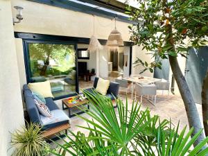 a patio with couches and a table in a house at Charmante Maison La Libournaise +parking in Libourne