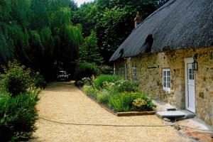 uma casa de pedra com um telhado de relva e um jardim em Afton Thatch: Beautiful Thatched Family Cottage em Freshwater