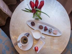 stolik z filiżanką kawy i wazę z czerwonymi kwiatami w obiekcie Soleil Boutique H w mieście Sopot