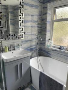 a bathroom with a white tub and a sink at Hidden Gem in Great Parndon