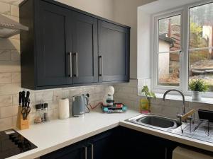 a kitchen with black cabinets and a sink and a window at Dumfries House By MGroupSA in Treherbert