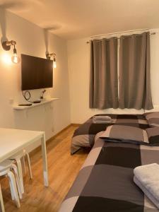 a room with two beds and a tv and a table at T2D Apartment - Suite BLG proche Disneyland Paris in Bussy-Saint-Georges