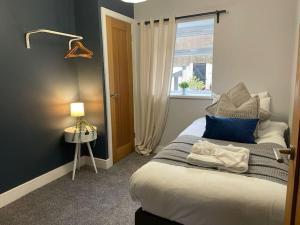 a bedroom with a bed with blue and white pillows at Dumfries House By MGroupSA in Treherbert