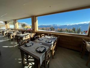 a restaurant with tables and chairs and a large window at Chalet Baita del Sole in Teglio