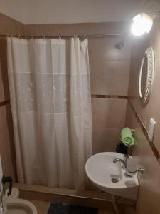 y baño con cortina de ducha y lavamanos. en Hosteria Catalina en Villa Carlos Paz