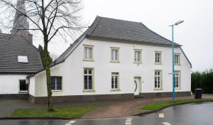 una casa blanca con techo negro en una calle en Work & Stay Apartment Bedburg Hau en Bedburg Hau