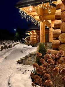 a log cabin in the snow with christmas lights at NA SKRAJU LASU domki z balią, jacuzzi in Biały Dunajec