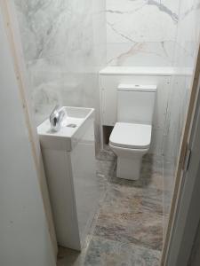 Baño blanco con aseo y lavamanos en Good priced double bed rooms in harrow with shared bathrooms en Hatch End