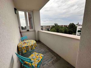 balcón con 2 sillas, mesa y ventana en Családbarát lakás Szombathely szívében, en Szombathely