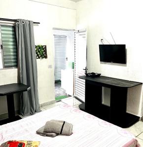 - un salon avec un lit et une télévision dans l'établissement Studio acolhedor em região central de Foz, à Foz do Iguaçu