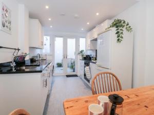 a kitchen with white cabinets and a wooden table at The Old Stores Annexe in Lyme Regis