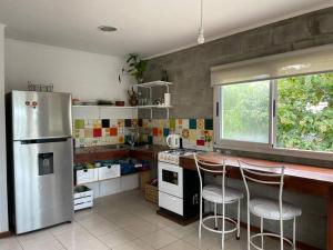 a kitchen with a stainless steel refrigerator and two bar stools at Casa Ingá in Parada Ayuí
