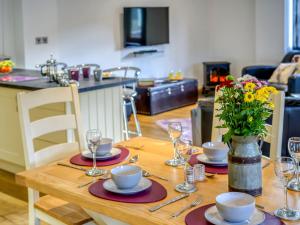 a wooden table with plates and glasses and a vase of flowers at 3 bed in Fowey 53664 in Warleggan