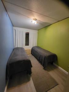 1 dormitorio con 2 camas y pared verde en Two bedroom apartment right next to Santapark, en Rovaniemi