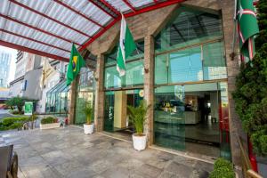 un bâtiment avec des drapeaux verts devant lui dans l'établissement Hotel Golden Park Curitiba, à Curitiba