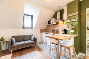 - une cuisine et une salle à manger avec une table et un canapé dans l'établissement Le Nid de Bien-être Appartement avec Balneo - 284, à Rouen