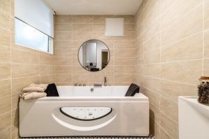 La salle de bains est pourvue d'une baignoire blanche et d'un miroir. dans l'établissement Le Nid de Bien-être Appartement avec Balneo - 284, à Rouen