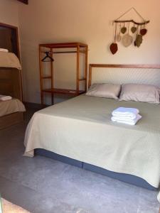 Chalé Buriti في بونيتو: غرفة نوم بسرير كبير عليها منشفة
