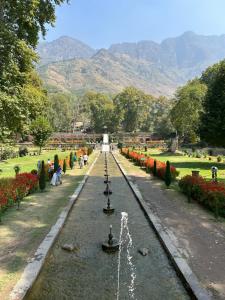 a fountain in a garden with mountains in the background at Houseboat Bendmeer Heritage in Srinagar