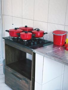 a group of four red pots on a stove in a kitchen at Casa de Praia Beira Mar Bali Beach House in Bertioga
