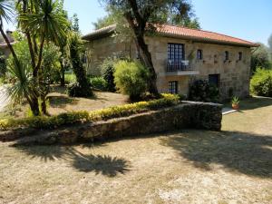 ein Steinhaus mit einer Palme davor in der Unterkunft Quinta de São Simão Turismo e Eventos in Vieira do Minho