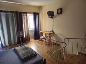 una camera con letto, scrivania e TV di caboverde-houses a Mindelo
