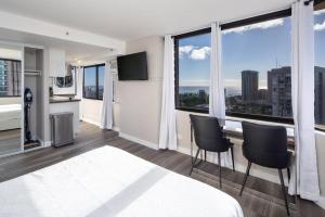 um quarto com uma cama e cadeiras e uma grande janela em Private Modern Luxury Corner Studio Ocean View em Honolulu