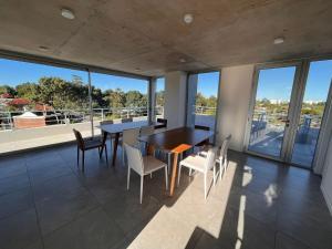 ein Esszimmer mit Tischen, Stühlen und großen Fenstern in der Unterkunft Edificio Pinheiros in Punta del Este