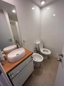 a white bathroom with a sink and a toilet at Edificio Pinheiros in Punta del Este