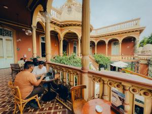 dos hombres sentados frente a un edificio con sus portátiles en Viajero Kokopelli Lima - Barranco Hostel en Lima