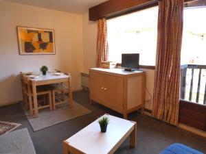 a living room with a desk and a table with a computer at Charmant studio à 1er étage, 4 pers., balcon, salle fitness, park, ski, jacuzzi - St Lary Soulan - FR-1-457-252 in Vignec