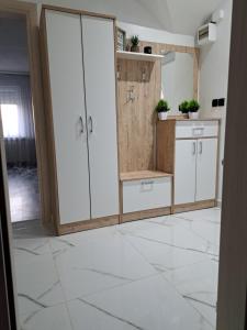 a kitchen with white cabinets and a tile floor at Apartman Mihaela in Laktaši